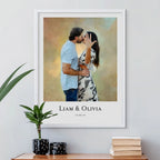 Oil-style portrait of a couple kissing, the woman showing a ring, in a white frame above a table with plants and books