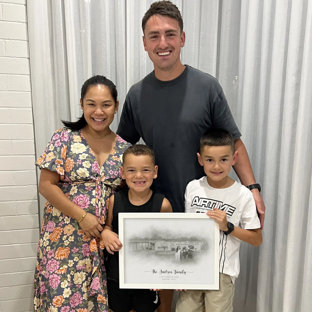 A woman, a man and two boys smile for the camera; a boy holds a white-framed sketch-style portrait of a house with a family