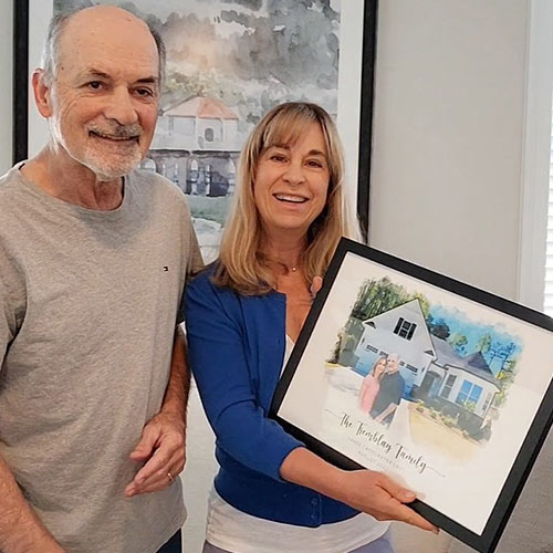 A couple holding a framed portrait of their house