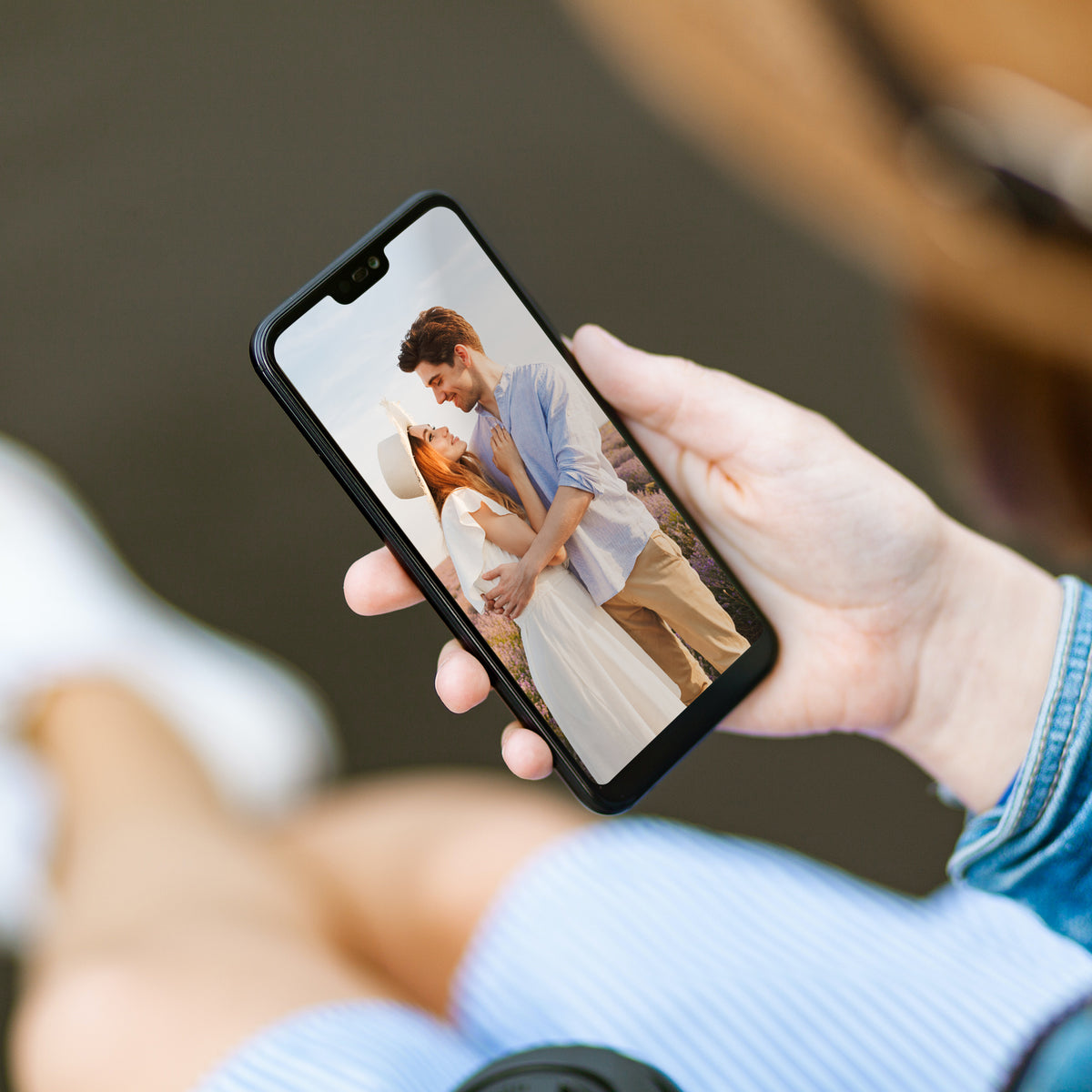 A hand holding a phone that shows a photo of a couple