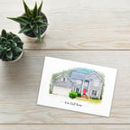 Postcard printed with a watercolor-style portrait of a house with a red door, titled 'Our first home', by two succulents