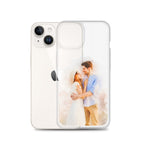 Clear iPhone 14 case printed with a watercolor-style portrait of a couple embracing, beside a white iPhone